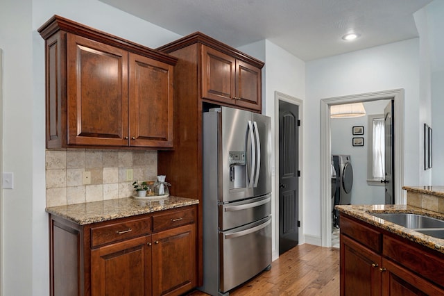 1421 N Rockingham Ave, Nixa, MO 65714 - kitchen with washer and clothes dryer, stainless steel fridge, wood finished floors, tasteful backsplash, and light stone counters