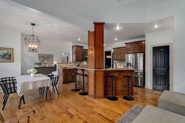 1421 N Rockingham Ave, Nixa, MO 65714 - kitchen with a kitchen breakfast bar, tasteful backsplash, appliances with stainless steel finishes, light wood finished floors, and light stone countertops