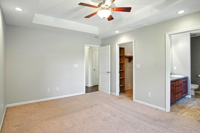 184 Crestwood Dr, Marshfield, MO 65706 - unfurnished bedroom featuring a tray ceiling, light carpet, a walk in closet, connected bathroom, and recessed lighting