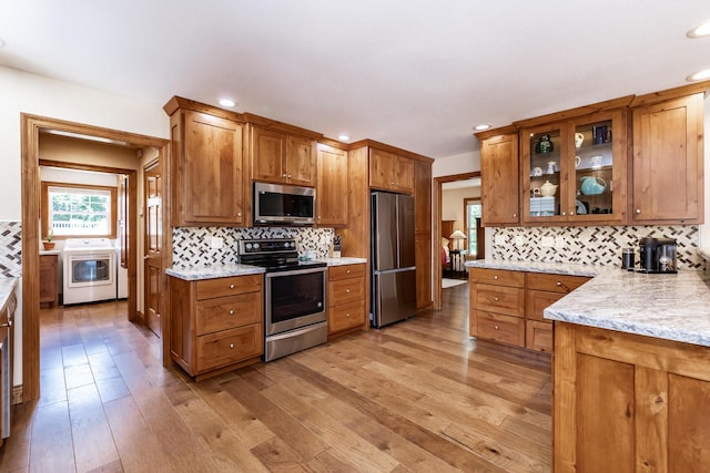 120 E Kennedy Blvd, Buffalo, MO 65622 - kitchen featuring stainless steel appliances, washer / clothes dryer, brown cabinetry, decorative backsplash, and light wood-type flooring