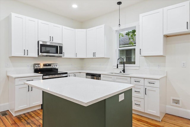 1156 W Lynn St, Springfield, MO 65802 - kitchen with appliances with stainless steel finishes, light wood-style flooring, light countertops, a center island, and white cabinetry