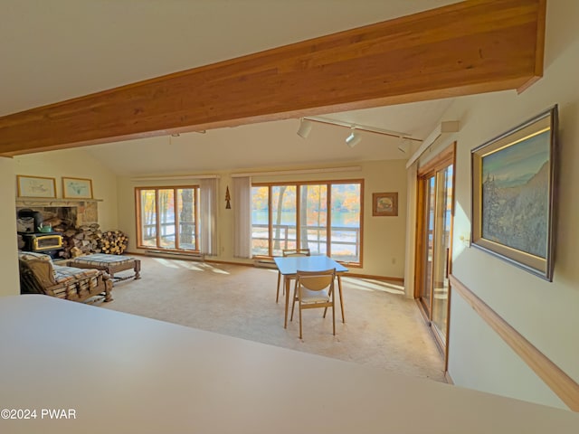 living room with vaulted ceiling with beams, light colored carpet, a wood stove, and track lighting