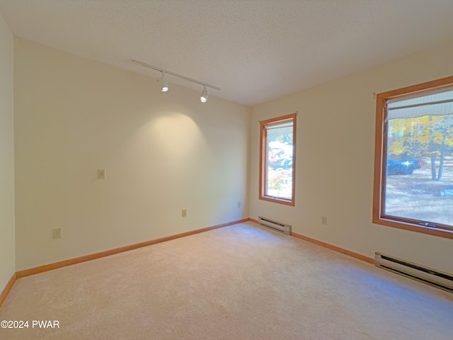 carpeted empty room with a textured ceiling, rail lighting, and baseboard heating