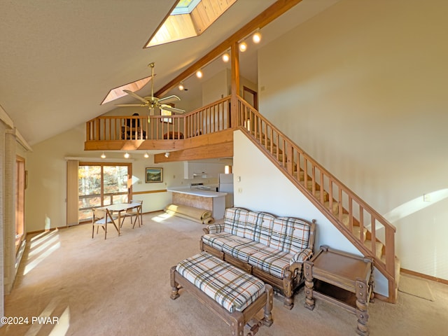 carpeted living room featuring a skylight, high vaulted ceiling, and ceiling fan