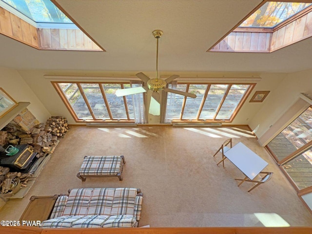 carpeted living area featuring a skylight, a ceiling fan, and a fireplace