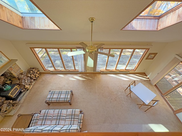 unfurnished living room featuring a high ceiling, a wood stove, a wealth of natural light, and ceiling fan