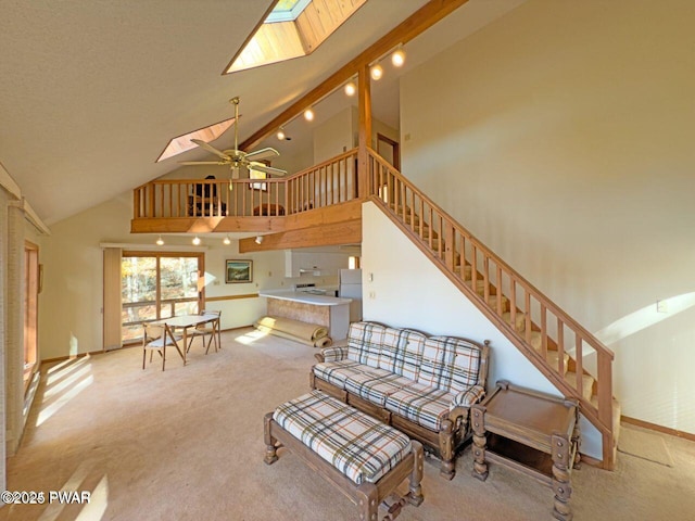living room with high vaulted ceiling, a skylight, a ceiling fan, and carpet