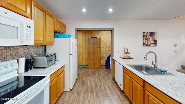 kitchen with white appliances, sink, decorative backsplash, light stone countertops, and light hardwood / wood-style floors