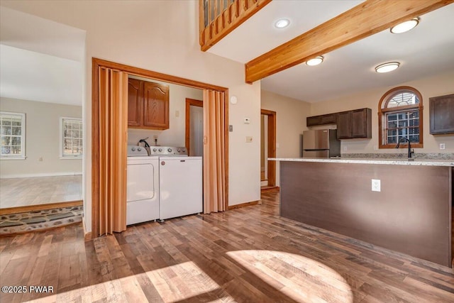 kitchen with washer and dryer, beam ceiling, wood finished floors, and freestanding refrigerator