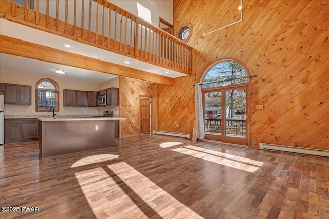 unfurnished living room with baseboard heating, plenty of natural light, a baseboard heating unit, and dark wood-style flooring