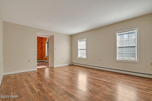 unfurnished room featuring wood finished floors, baseboards, and baseboard heating