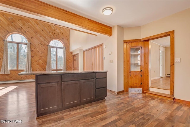 interior space with a baseboard heating unit, wood finished floors, and baseboards