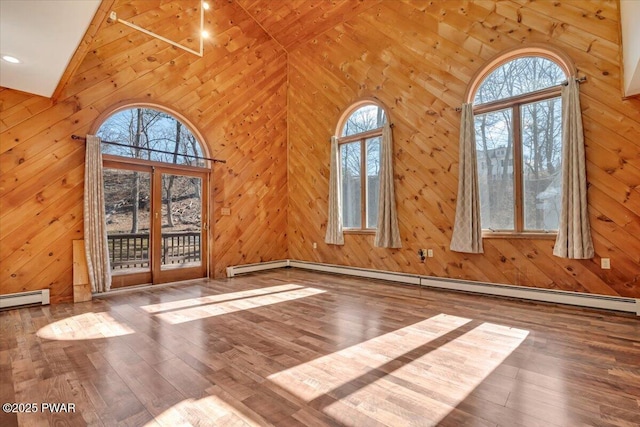 unfurnished living room with a wealth of natural light, high vaulted ceiling, and wood finished floors