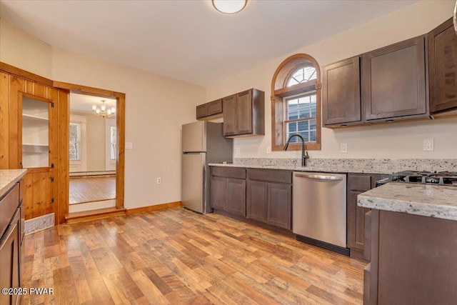 kitchen with light stone countertops, visible vents, stainless steel appliances, a baseboard heating unit, and light wood-type flooring