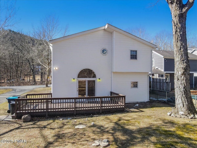 rear view of property featuring a deck, a yard, and fence