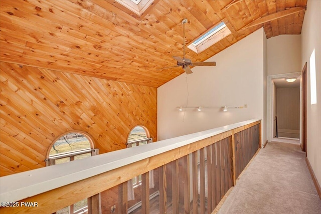 corridor featuring wood ceiling, high vaulted ceiling, a skylight, and carpet floors