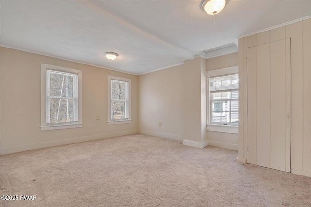 carpeted spare room with crown molding and baseboards