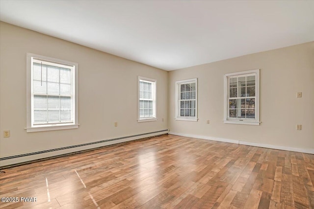 spare room featuring a wealth of natural light, light wood-type flooring, baseboards, and baseboard heating