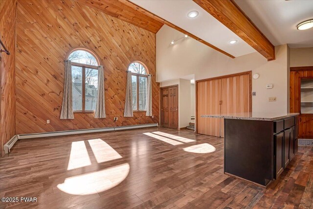 interior space with light stone counters, beamed ceiling, dark wood finished floors, and wood walls