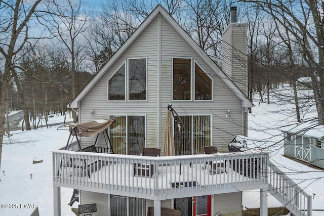 snow covered back of property with a wooden deck