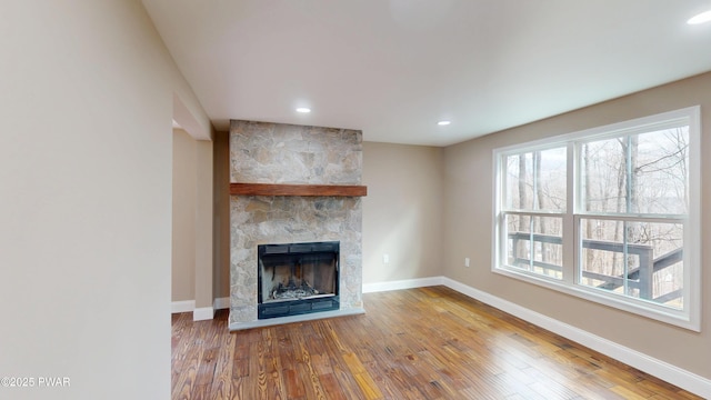 unfurnished living room with recessed lighting, a fireplace, baseboards, and wood finished floors