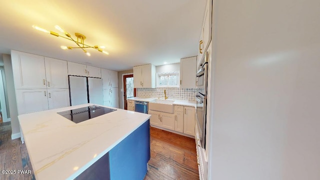 kitchen featuring appliances with stainless steel finishes, a center island, a sink, white cabinetry, and backsplash