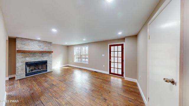 unfurnished living room featuring recessed lighting, a fireplace, wood finished floors, and baseboards