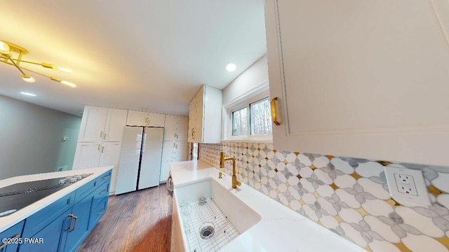 kitchen featuring dark wood-style floors, decorative backsplash, freestanding refrigerator, white cabinets, and blue cabinets