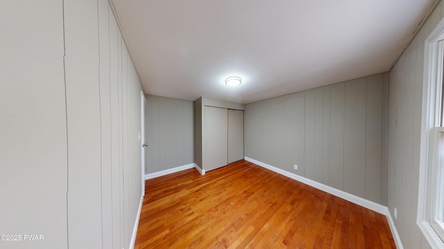 unfurnished bedroom featuring a closet, light wood-type flooring, and baseboards