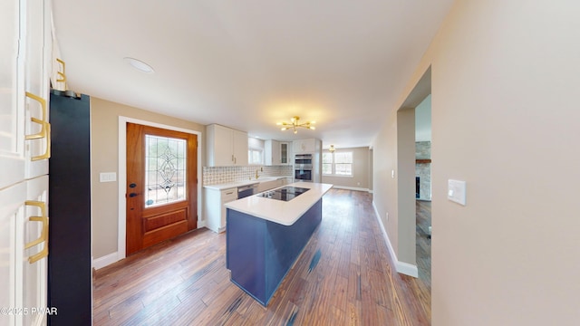 kitchen featuring dark wood-style flooring, tasteful backsplash, light countertops, white cabinetry, and black appliances