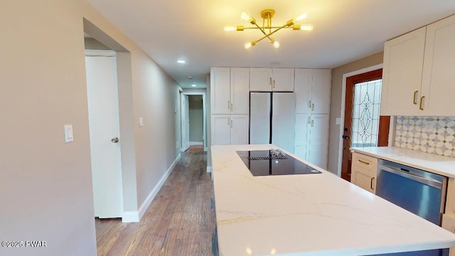 kitchen featuring black electric cooktop, stainless steel dishwasher, backsplash, freestanding refrigerator, and a center island