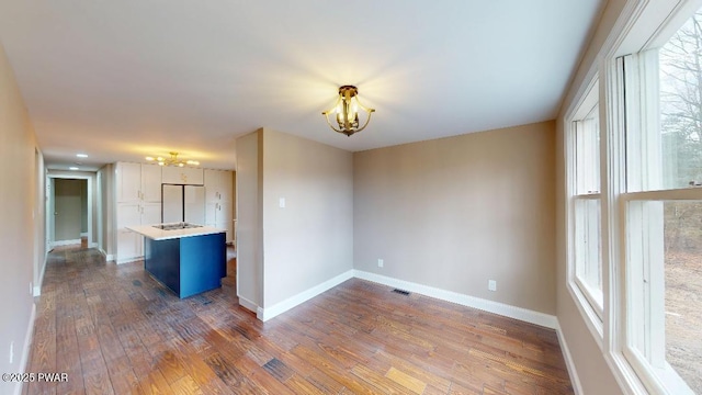 interior space featuring baseboards, dark wood finished floors, visible vents, and a notable chandelier