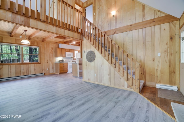 unfurnished living room with wooden walls, light wood finished floors, a baseboard radiator, stairs, and beam ceiling