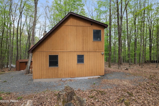view of side of home with an outbuilding, a storage shed, and a chimney