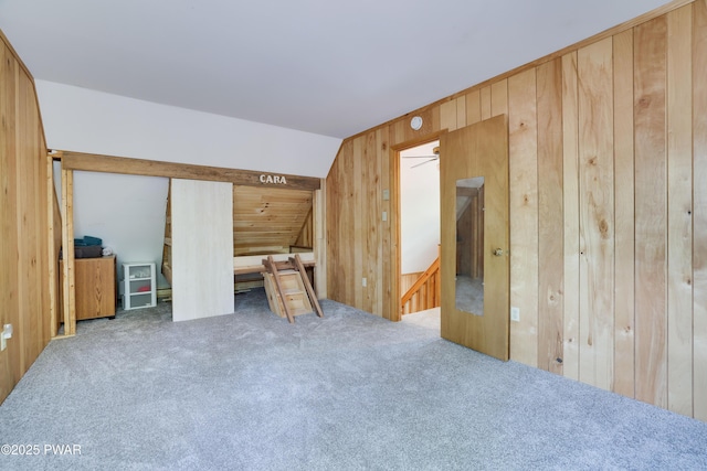 additional living space with wood walls and carpet