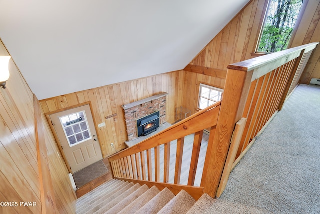 staircase featuring wood walls, vaulted ceiling, and carpet