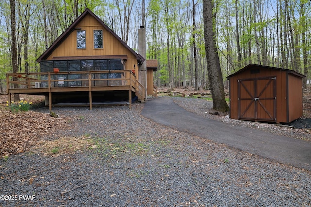view of property exterior featuring a deck, a shed, and an outbuilding