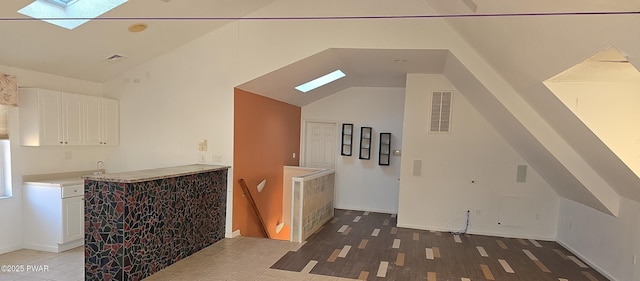 bonus room featuring visible vents, high vaulted ceiling, a skylight, and light wood finished floors