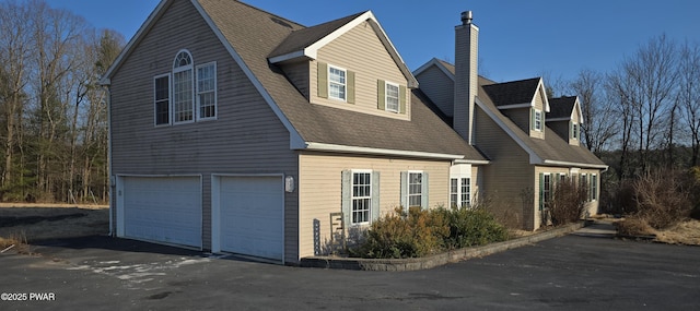 view of home's exterior featuring an attached garage and a shingled roof