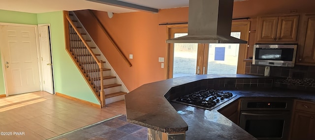 kitchen featuring beam ceiling, tasteful backsplash, stainless steel appliances, island range hood, and baseboards