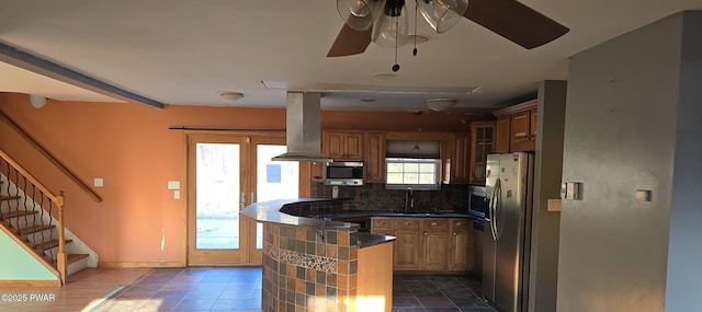 kitchen featuring a sink, tasteful backsplash, dark countertops, appliances with stainless steel finishes, and island range hood