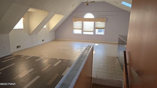 bonus room featuring tile patterned flooring, visible vents, vaulted ceiling with skylight, and baseboards