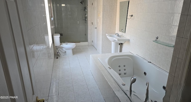 bathroom featuring tile patterned floors, toilet, a stall shower, a jetted tub, and tile walls