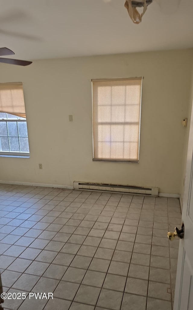 spare room with a baseboard radiator, baseboards, light tile patterned flooring, and a ceiling fan