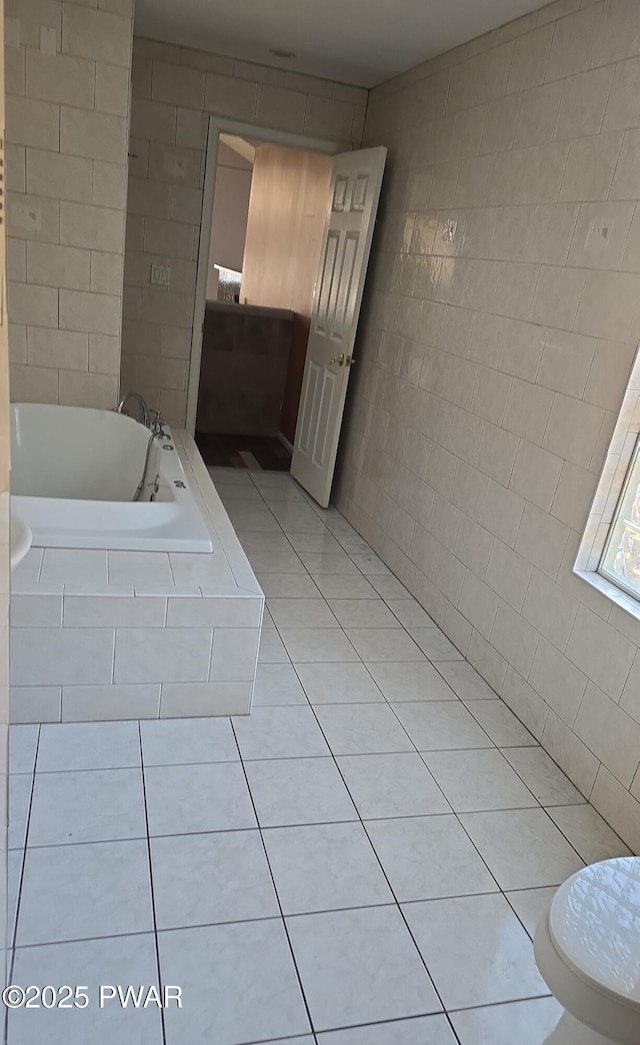 bathroom featuring tile patterned floors, a bath, and tile walls