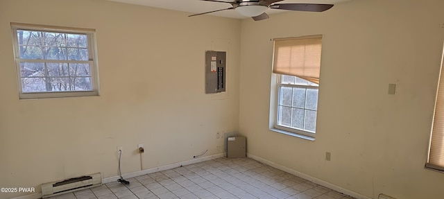 spare room with light tile patterned floors, a ceiling fan, baseboards, electric panel, and a baseboard heating unit