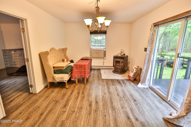 174 Laverne Dr, Dingmans Ferry, PA 18328 - sitting room with wood finished floors, a wood stove, a chandelier, and a baseboard radiator
