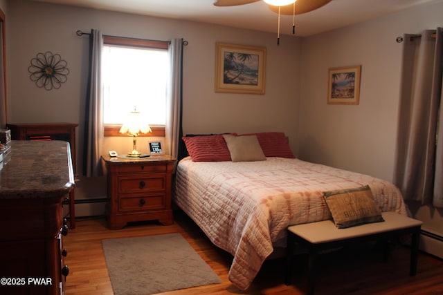 bedroom featuring ceiling fan, light hardwood / wood-style flooring, and a baseboard heating unit