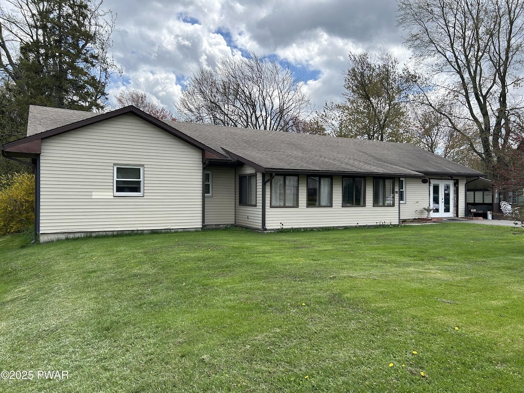 ranch-style home with roof with shingles, french doors, and a front yard