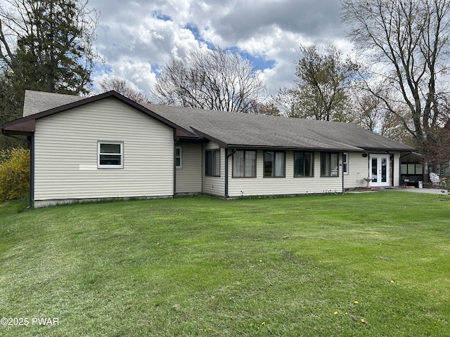 ranch-style home with roof with shingles, french doors, and a front yard